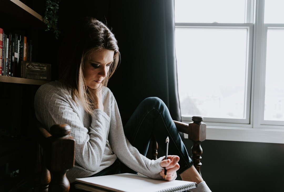 Brazilian woman writing notes at a desk surrounded by books